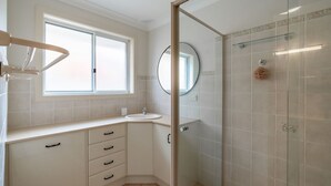 Une salle de bain moderne avec une fenêtre, un lavabo, un miroir et une douche à parois de verre.