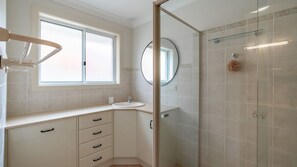 Een moderne badkamer met raam, wastafel, spiegel en douchecabine.