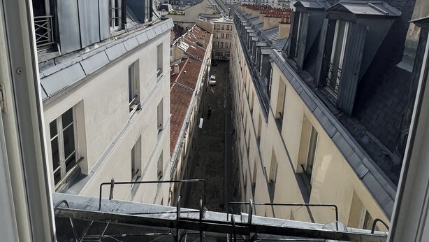 Un estrecho callejón entre edificios, con cielo despejado y luz solar.
