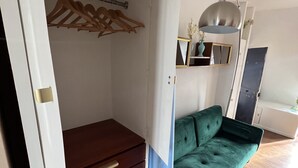 Una habitación con un sofá verde, un aparador de madera y un armario ropero.