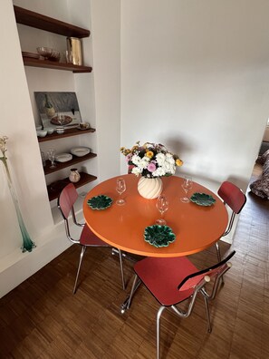 Uma mesa de jantar com quatro cadeiras, um vaso de flores e um quadro na parede.