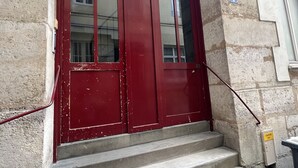 Una puerta roja con dos paneles de vidrio, un pasamanos de metal y una escalera de concreto que lleva a la entrada de un edificio.