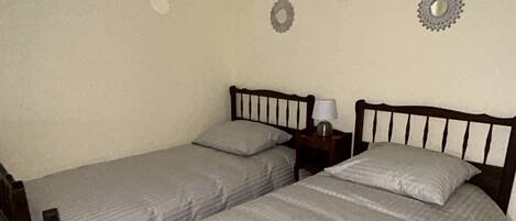 Une chambre avec deux lits simples, une table de chevet avec une lampe et des éléments décoratifs fixés au mur.