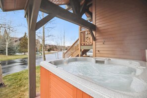 Ein Whirlpool auf einer Holzterrasse mit Blick auf eine Wohnstraße und Häuser im Hintergrund.