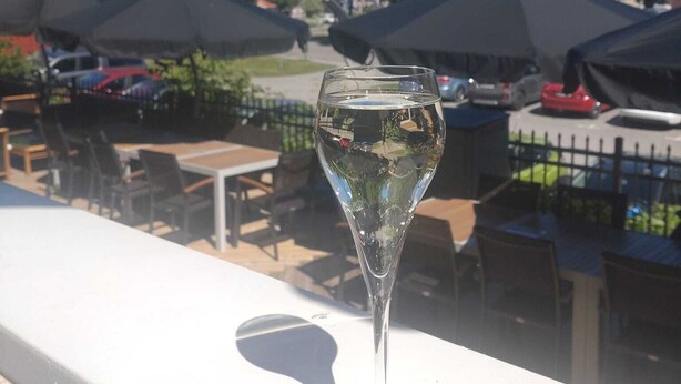 Ett glas vatten på en balkong med utomhusmöbler och parasoller.