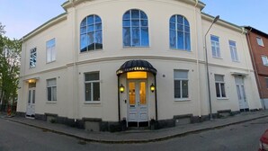 En tvåvåningsbyggnad med en böjd fasad, stora, välvda fönster och en skylt med texten ”HOTEL TEMPERANCE”.