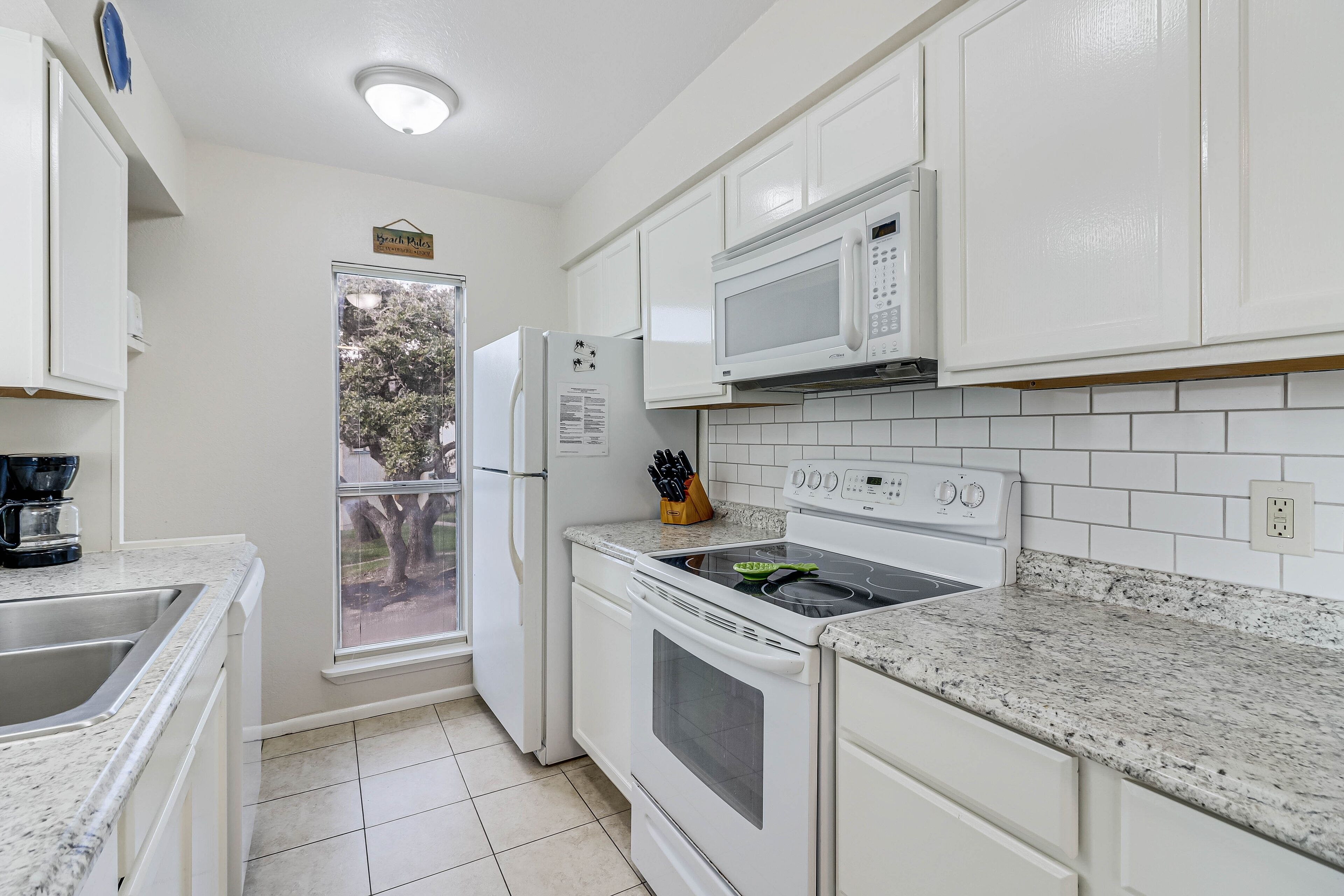 A modern kitchen with white cabinets, a microwave, an oven, and a granite countertop.