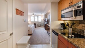 A compact kitchen with a microwave, coffee maker, and a dish rack. There is a small seating area with a chair and a table. - Premium Unit 4643- Fraser Crossing/founders Pointe Condo (Winter Park)