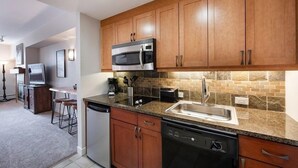 A modern kitchen with wooden cabinets, a granite countertop, stainless steel appliances, and a tiled backsplash. - Premium Unit 4643- Fraser Crossing/founders Pointe Condo (Winter Park)