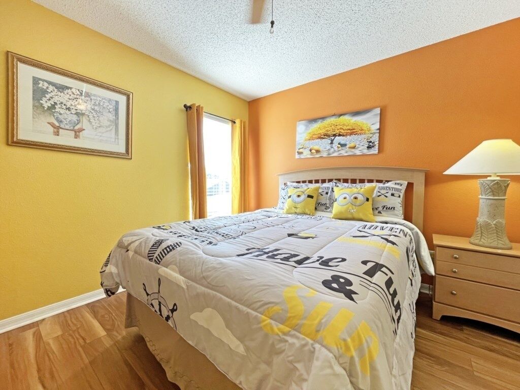 A bedroom with a bed, a nightstand, a lamp, and two paintings on the wall.