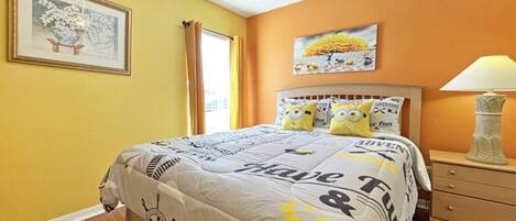 A bedroom with a bed, a nightstand, a lamp, and two paintings on the wall.