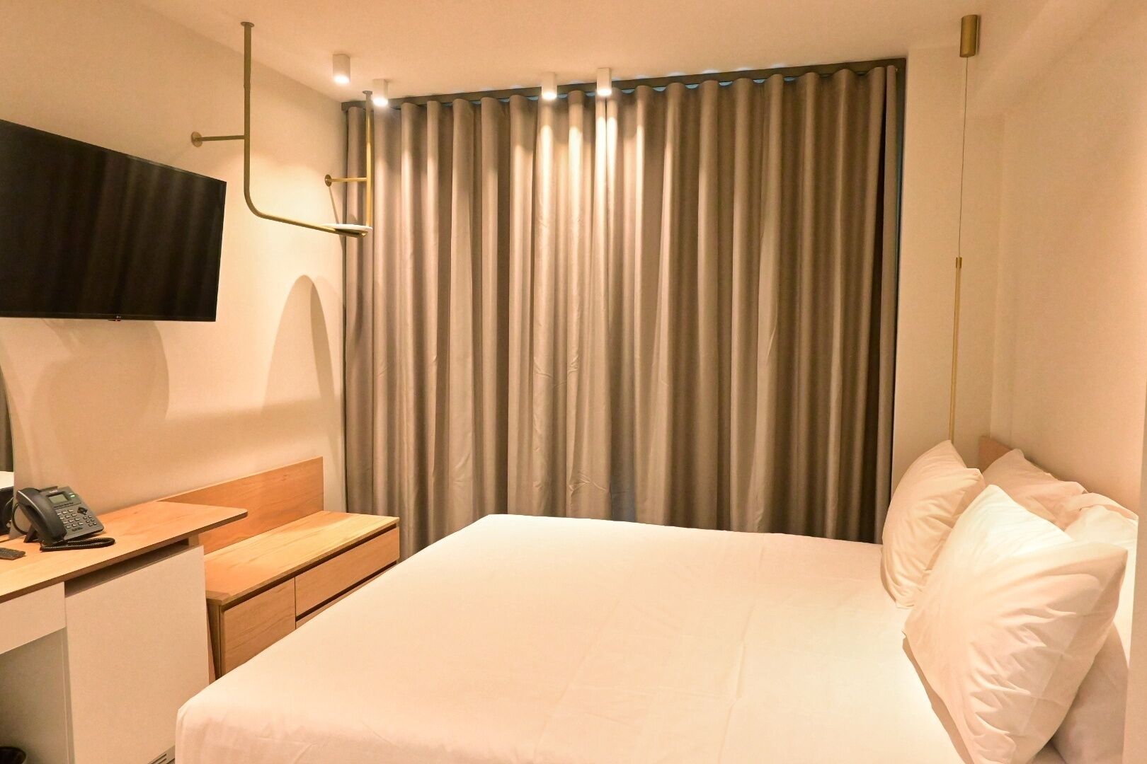 Una habitación de hotel con una cama, un escritorio con teléfono y una cortina.