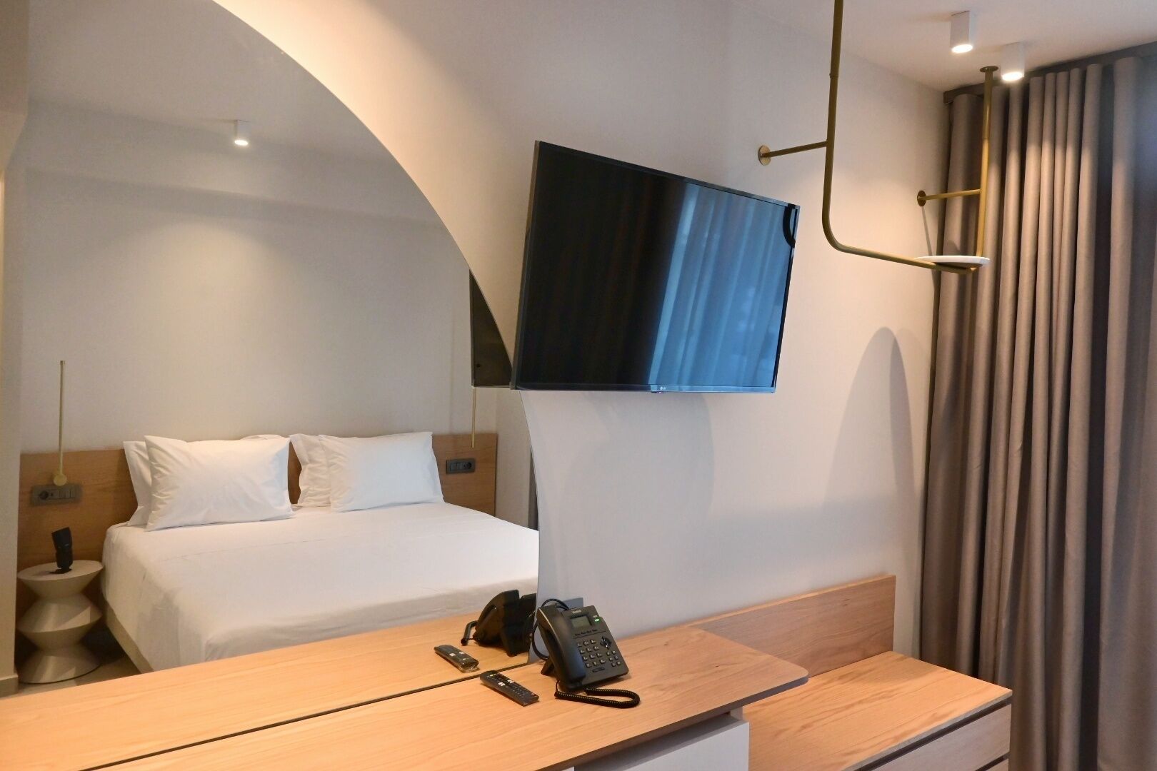 Een hotelkamer met een bed, nachtkastje en een wandtelevisie.