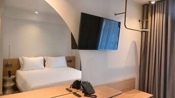 Een hotelkamer met een bed, nachtkastje en een wandtelevisie.
