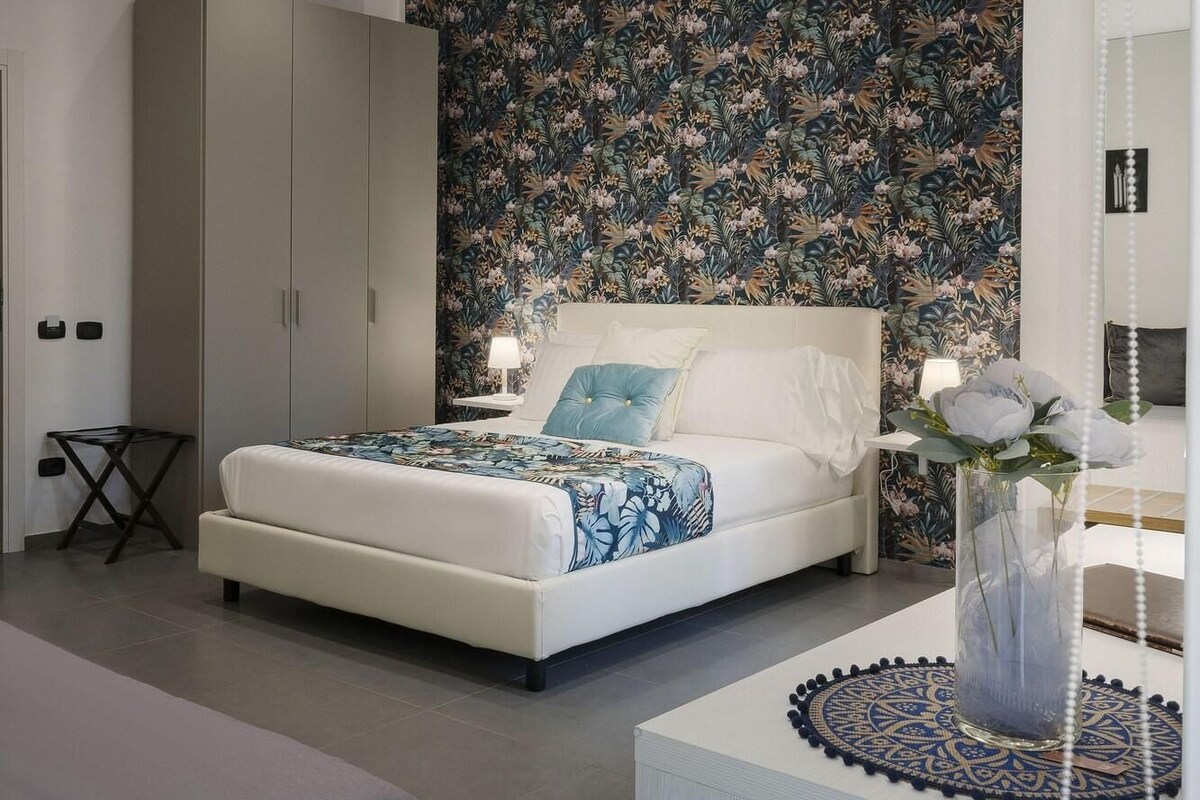 A modern bedroom with a large bed, a wardrobe, and a decorative wall.