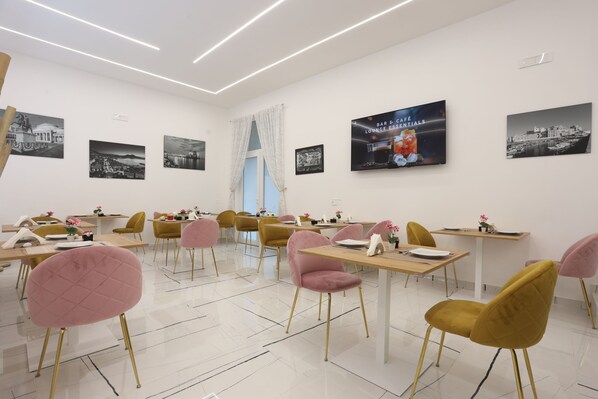 A dining area with tables and chairs, a large window with curtains, and wall art. - PALAZZO SANT'ARCANGELO (Naples)