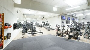 A gym with various exercise equipment, a mirror, and a wooden ladder.
