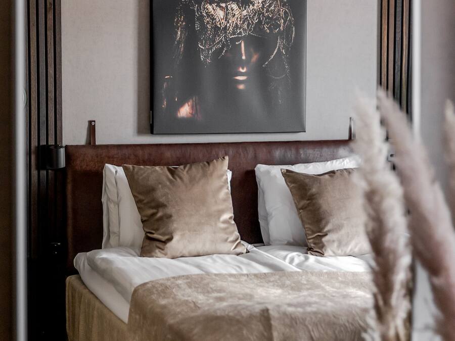 Quarto com uma cama grande, cabeceira e uma obra de arte na parede.