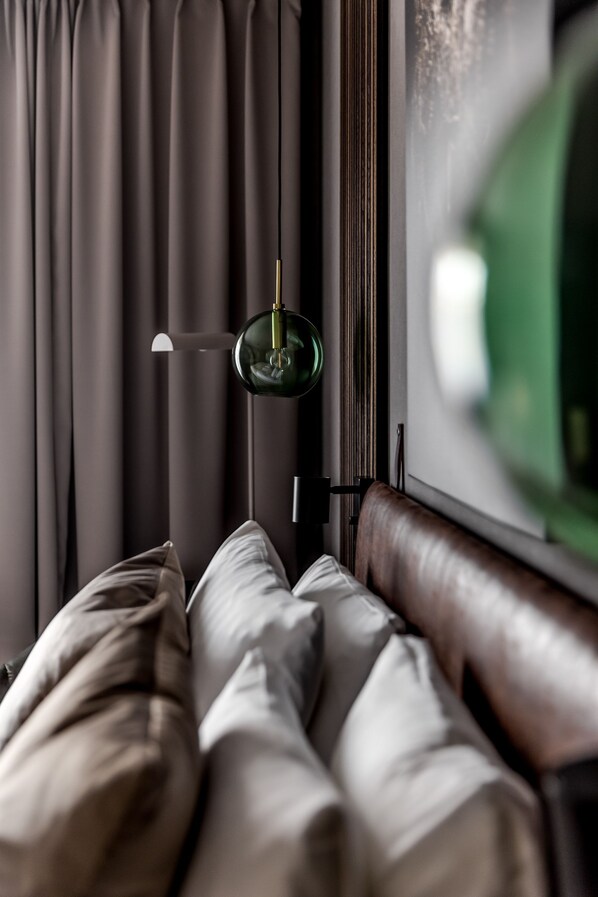 A bedroom with a bed, a nightstand, a lamp, and a window with curtains. - XHOTEL (Ludvika)
