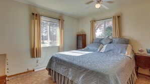 A bedroom with a large bed, a wooden nightstand, a dresser, and a window with curtains. - Family-friendly Home w/ Fire Pit ~ 10 Mi to Akron! (Akron)