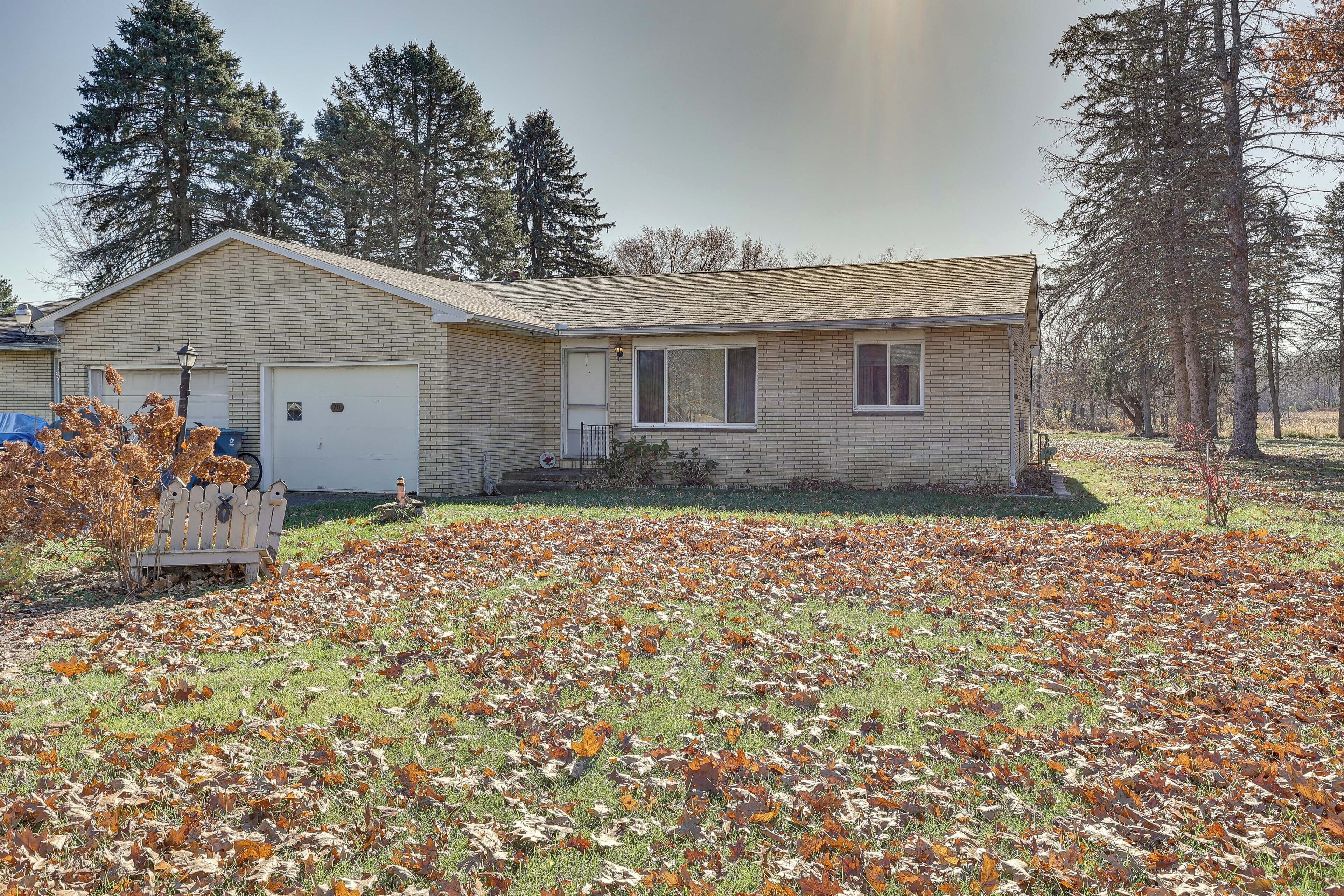 A single-story house with a garage, surrounded by a yard covered in fallen leaves.