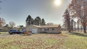A residential house with a garage, a driveway, and a lawn covered with fallen leaves. - Family-friendly Home w/ Fire Pit ~ 10 Mi to Akron! (Akron)