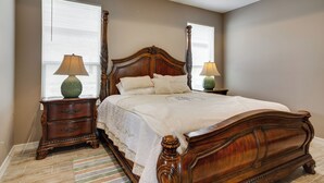 A bedroom with a large bed, two nightstands, and a window with blinds.