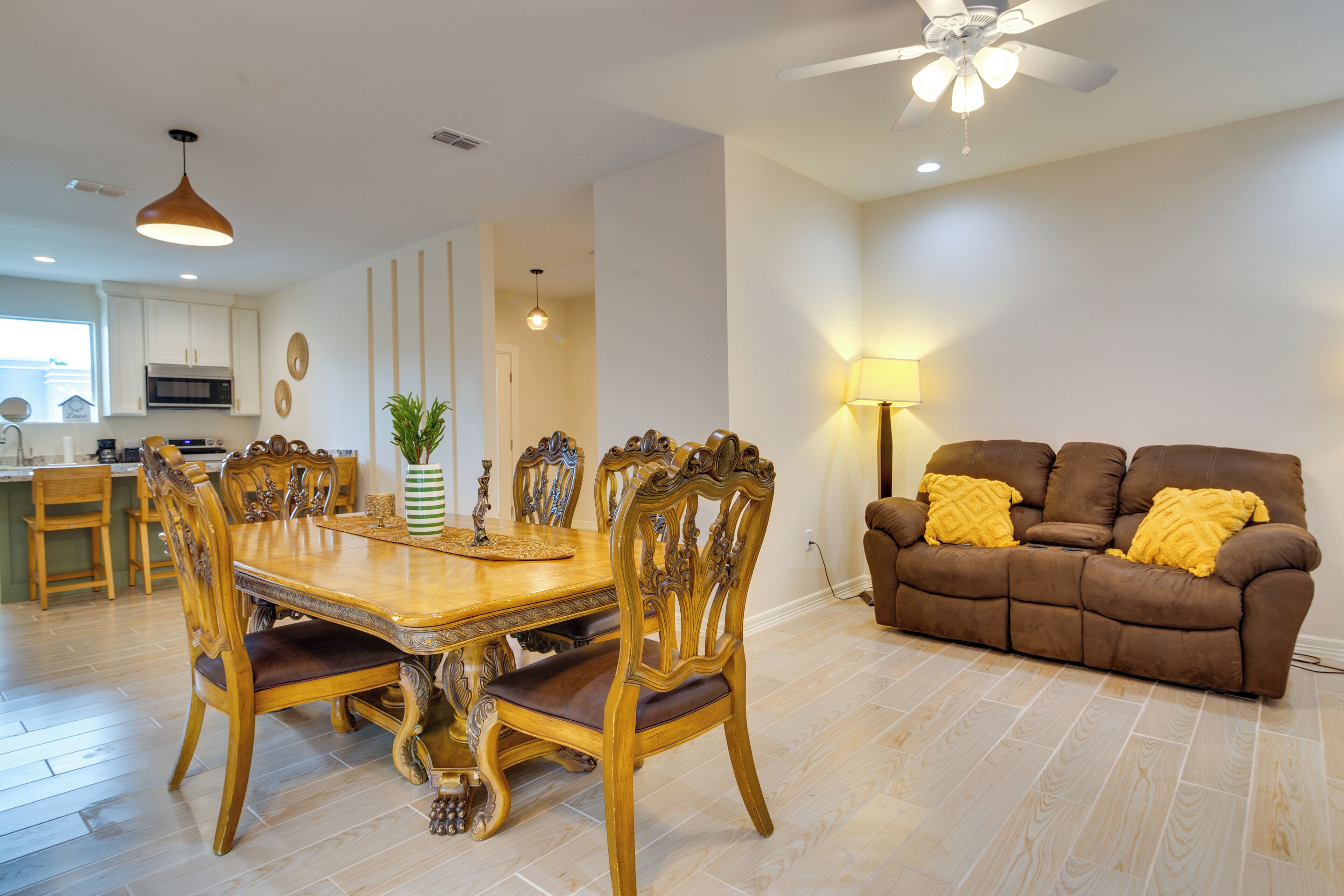 A modern kitchen with white cabinets, a built-in oven, and a dining area with a wooden table and chairs.