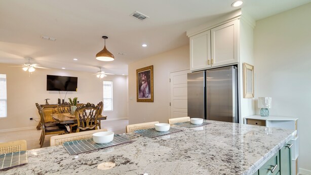 A modern kitchen with a large marble island, built-in appliances, and a dining area with wooden chairs and a table.