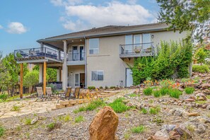 Ein zweistöckiges Haus mit Balkon, Sitzgelegenheit im Freien und einem angelegten Garten.