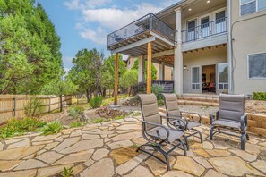 A patio with stone flooring and outdoor furniture, a wooden fence, and a two-story building with a balcony. - Summer Hikes! Mtn-view Gem w/ Hot Tub in Ruidoso (Ruidoso)