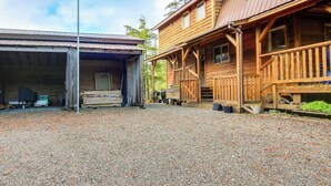 A rustic wooden building with a covered porch and a gravel driveway. - Forested Coffman Cove Cabin w/ Wood-burning Stove! (Coffman Cove)