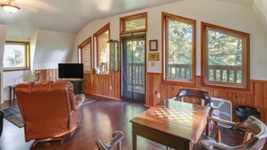 A spacious room with a large wooden table, leather chairs, a television, and large windows with a view of trees. - Forested Coffman Cove Cabin w/ Wood-burning Stove! (Coffman Cove)