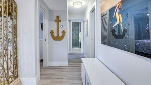Um corredor com piso de madeira, um banco branco e um aquário grande com peixes.
