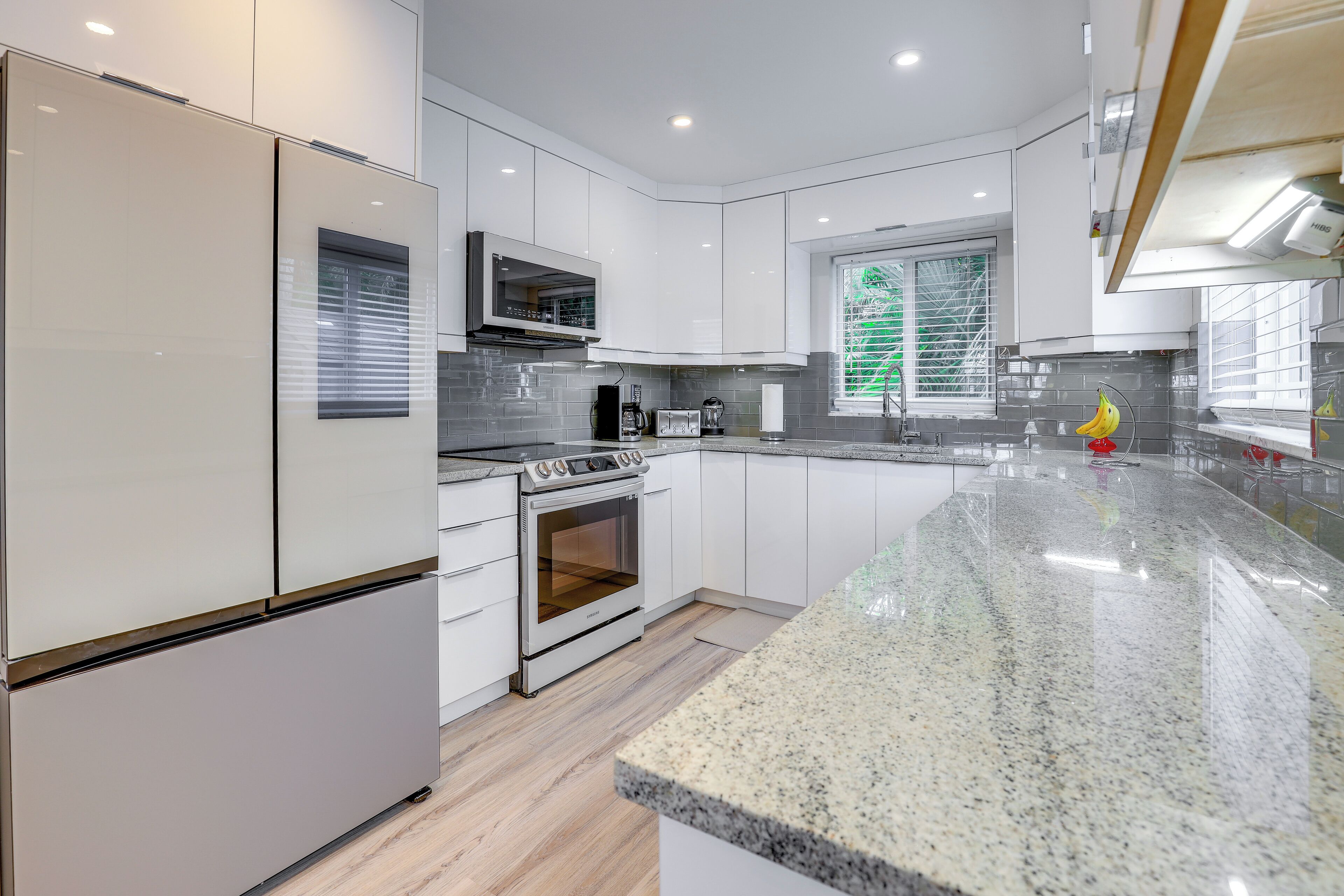 A modern kitchen with white cabinetry, a granite countertop, and stainless steel appliances.