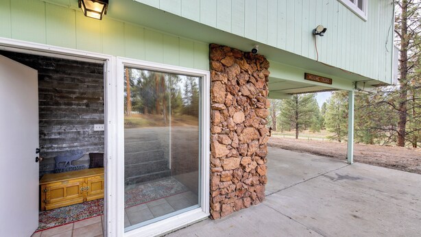 A building entrance with a stone wall, a welcome sign, and a wooden bench outside.