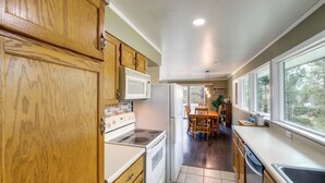 A kitchen with wooden cabinets, a white stove, a refrigerator, and a dining area with a table and chairs.