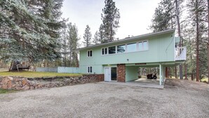 A two-story house with a stone foundation, a covered porch, and a vehicle parked outside.
