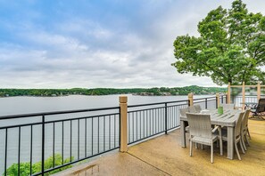 A terrace with a view of a lake, wicker furniture, and a railing. - Boat Slip & Water Views: Lake Ozark Condo (Lake Ozark)