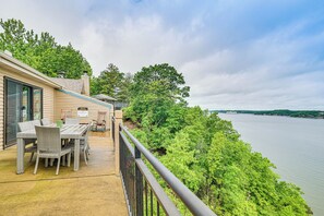 A balcony with wicker furniture overlooking a body of water, surrounded by greenery. - Boat Slip & Water Views: Lake Ozark Condo (Lake Ozark)