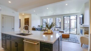 Una cocina moderna con una isla grande, electrodomésticos integrados y un comedor con sofá y mesa de centro.