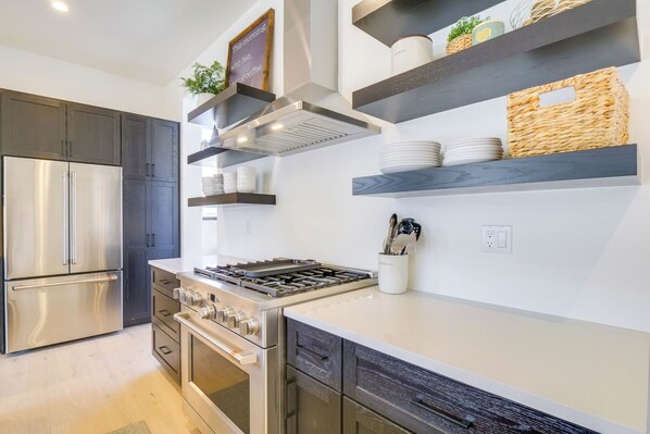 A modern kitchen with stainless steel appliances, wooden cabinets, and built-in shelves with decorative items.