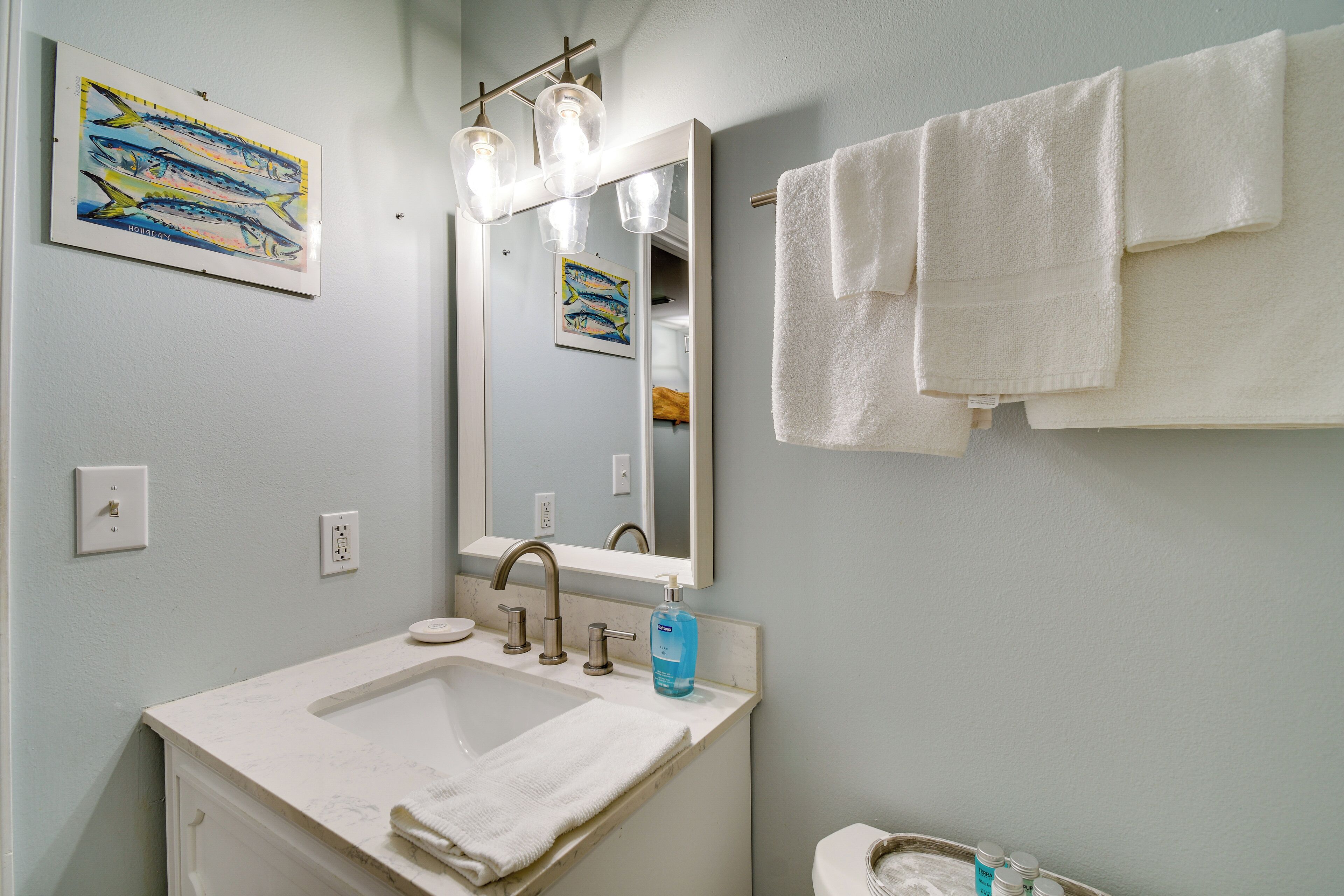A bathroom with a sink, mirror, and towels.
