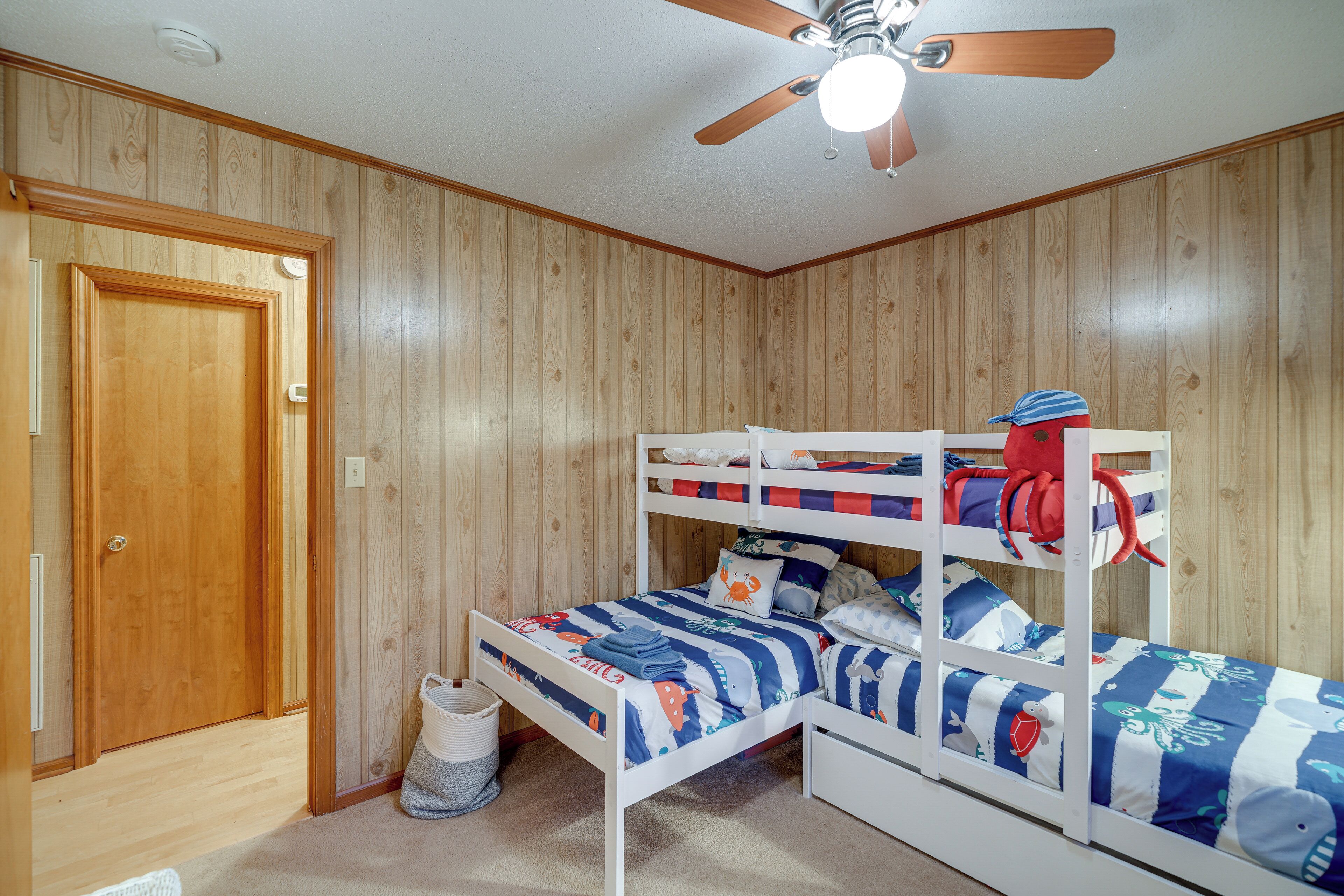 Un lit superposé avec un ventilateur de plafond, des murs en bois et une porte.