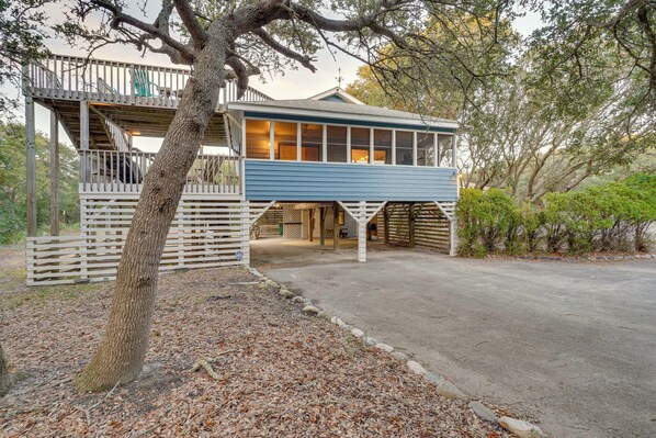 A two-story building with a blue exterior, a wooden deck, and a covered porch.