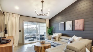 A modern living room with a sofa, coffee table, and a chandelier.