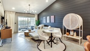 A modern living room with a sofa, round table, and a rattan chair.