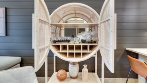 A modern interior with a central display unit featuring a wine bottle, glasses, and decorative items.