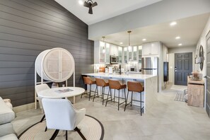 Una cocina moderna con una isla central, taburetes de bar y una mesa redonda con sillas.