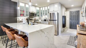 A modern kitchen with a large island, stainless steel appliances, and bar stools.